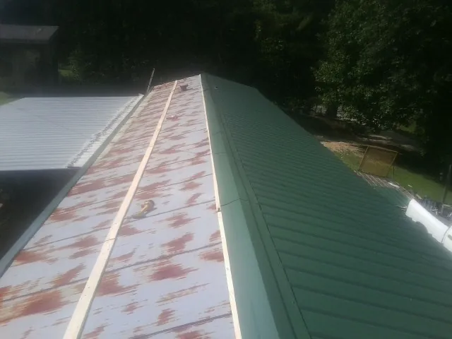 Old rusted panels beside newly installed green metal roofing — Wind Damage Roof Repair by Roofing Brothers in Hoosick Falls
