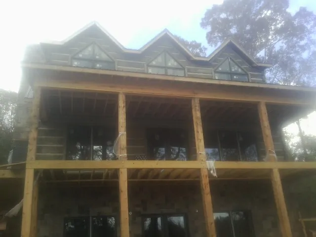 Dormers and porch framing on a large log home under construction — Roof Coating work by our crew in Hoosick Falls