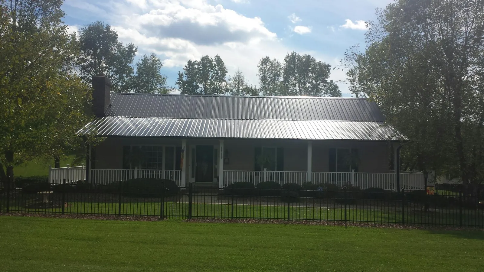 Gray metal roof on a brick ranch with a full width front porch — Gutter Guard Installation work by our crew in Hoosick Falls