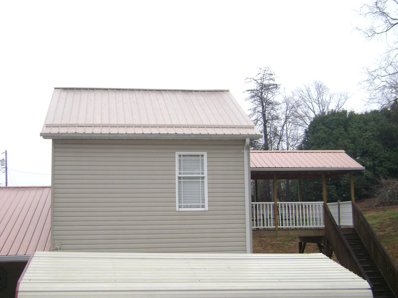 Tan metal roofs on a two story addition and attached porch, from a Roof Replacement job in Hoosick Falls