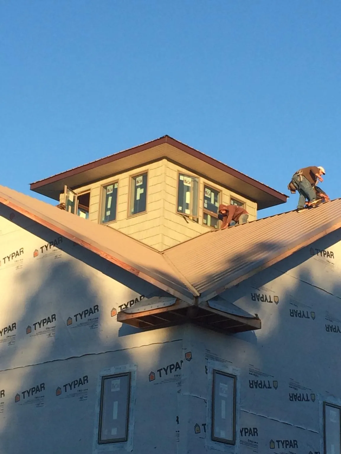 Roofers working around a rooftop cupola on a new metal roof at sunset — Roof Waterproofing in Hoosick Falls by Roofing Brothers